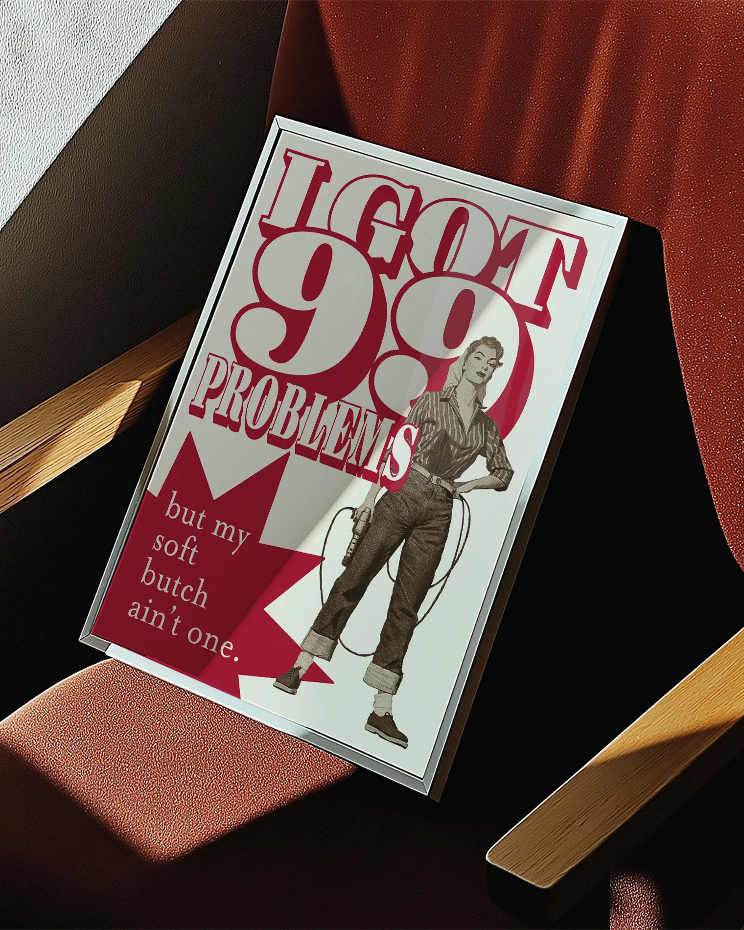 A framed poster depicting a soft butch wearing jeans and a shirt, holding a drill with the text: “I GOT 99 PROBLEMS” and “but my soft butch ain't one.”