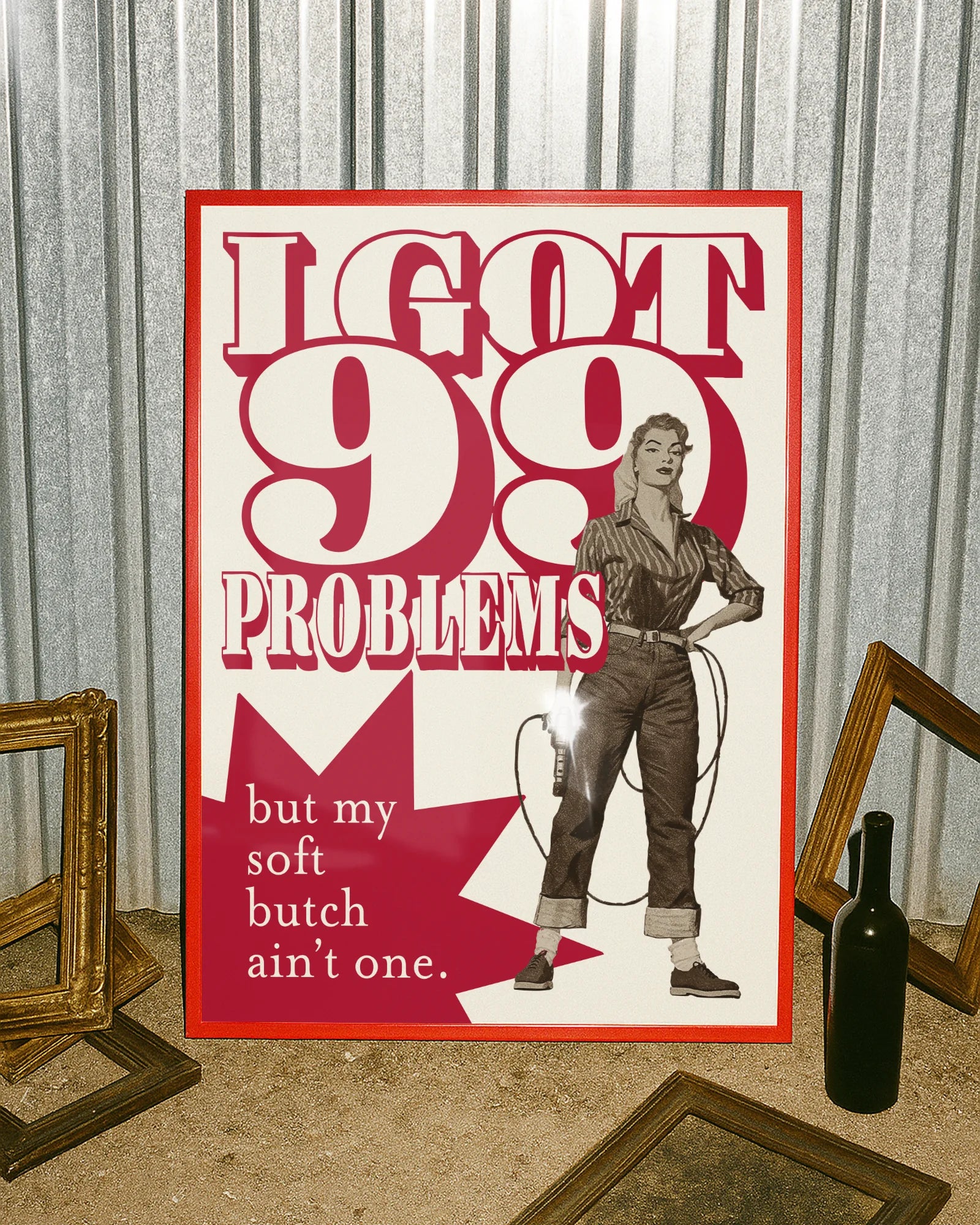 A framed poster depicting a soft butch wearing jeans and a shirt, holding a drill with the text: “I GOT 99 PROBLEMS” and “but my soft butch ain't one.”
