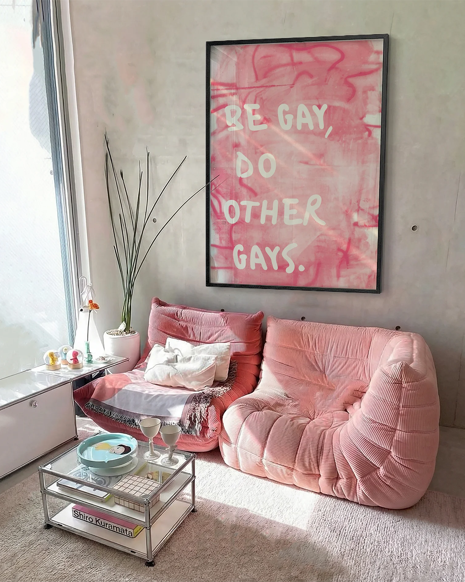 A framed poster with the text 'BE GAY, DO OTHER GAYS.', against a pink, abstract background.