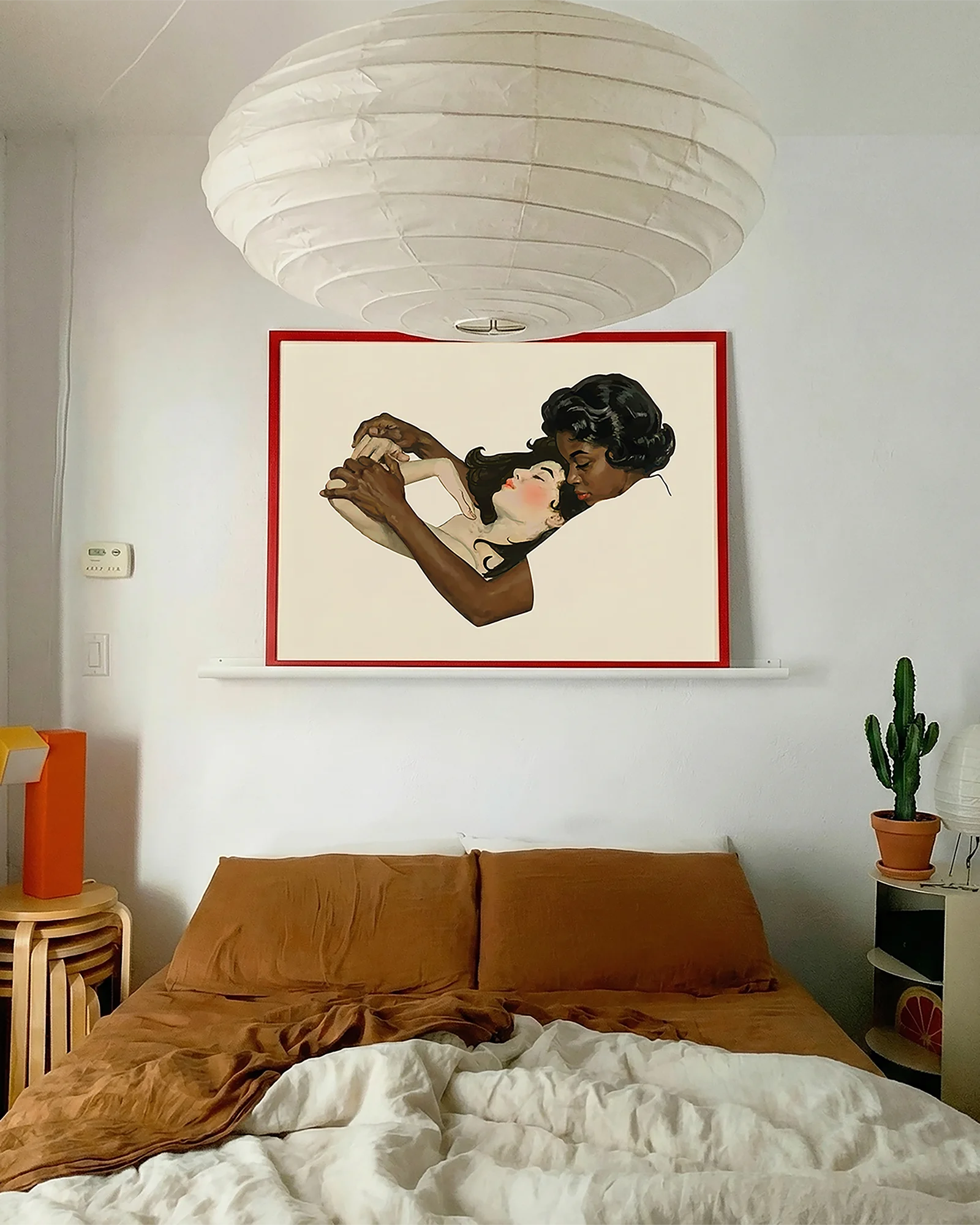 A framed, horizontal print with two lesbian women in a warm, romantic embrace.