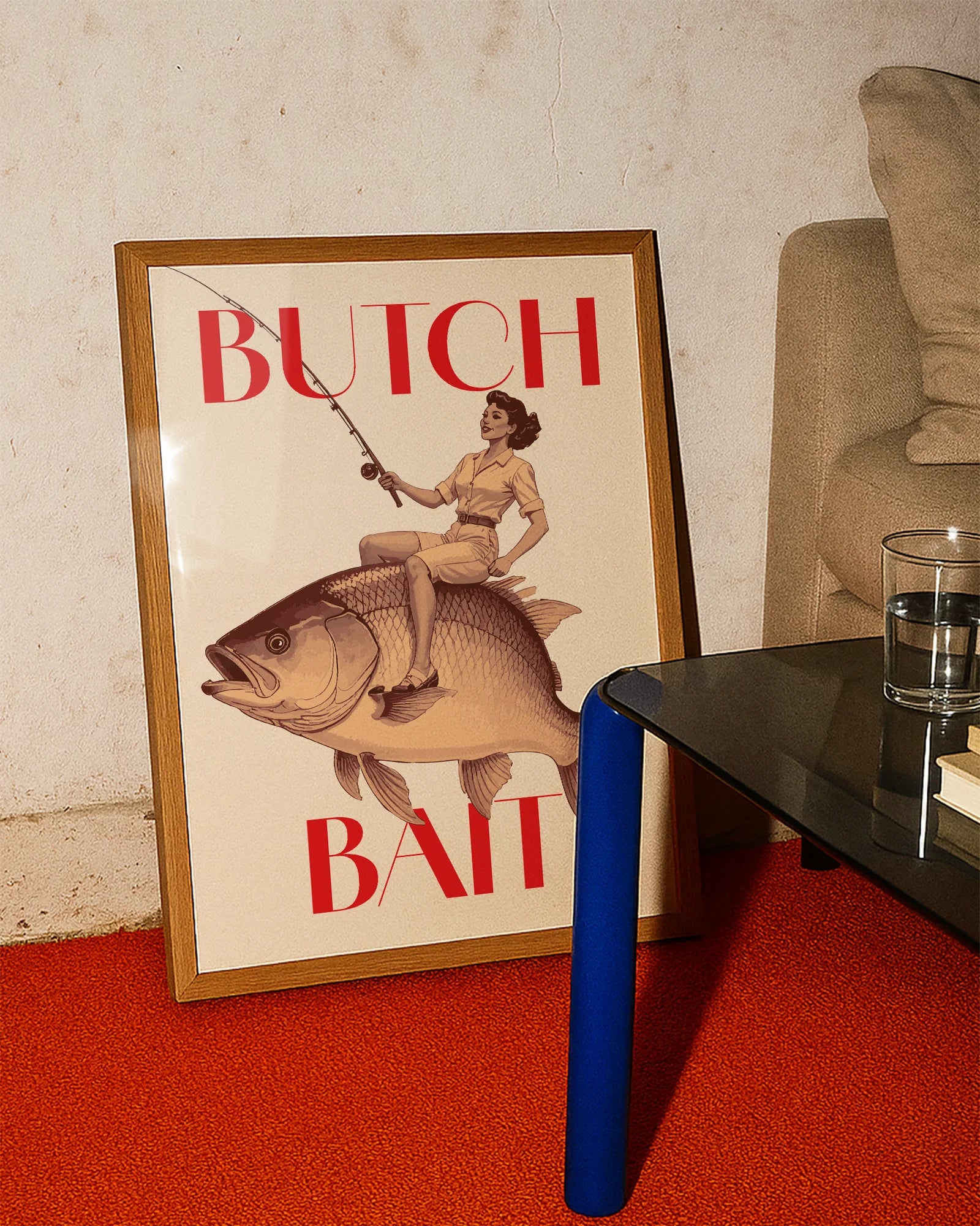 A poster depicting a lesbian woman riding a fish and holding a fishing rod, with the text ‘BUTCH BAIT'.