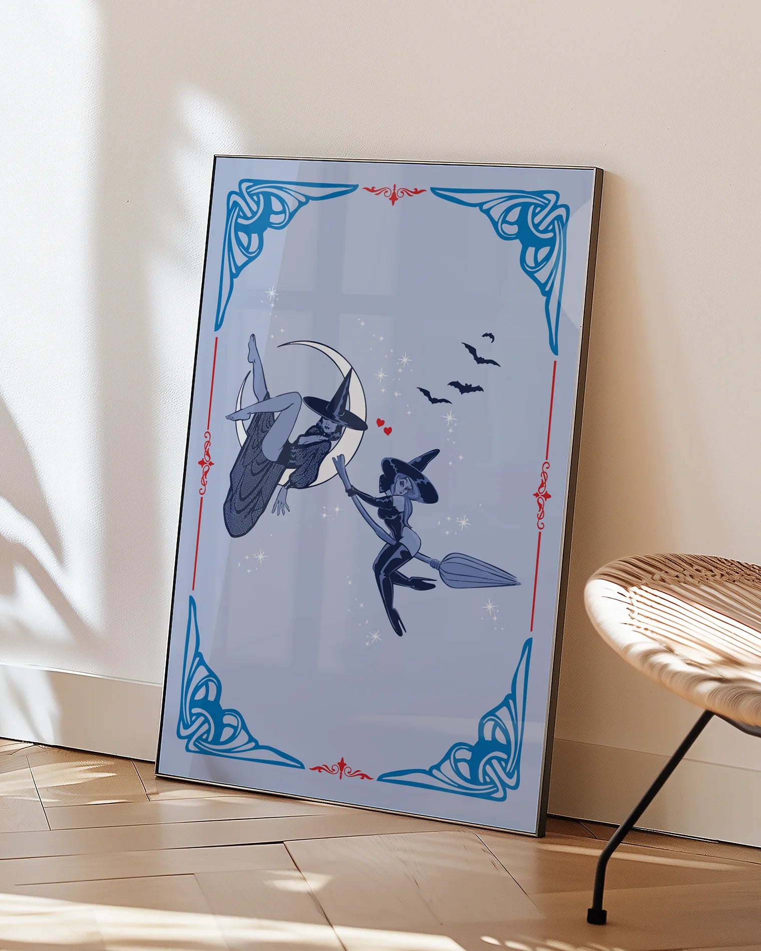 A poster featuring two lesbian witches—one flying on her broomstick while the other lies on the moon. They share a flirtatious glance, surrounded by stars and bats.