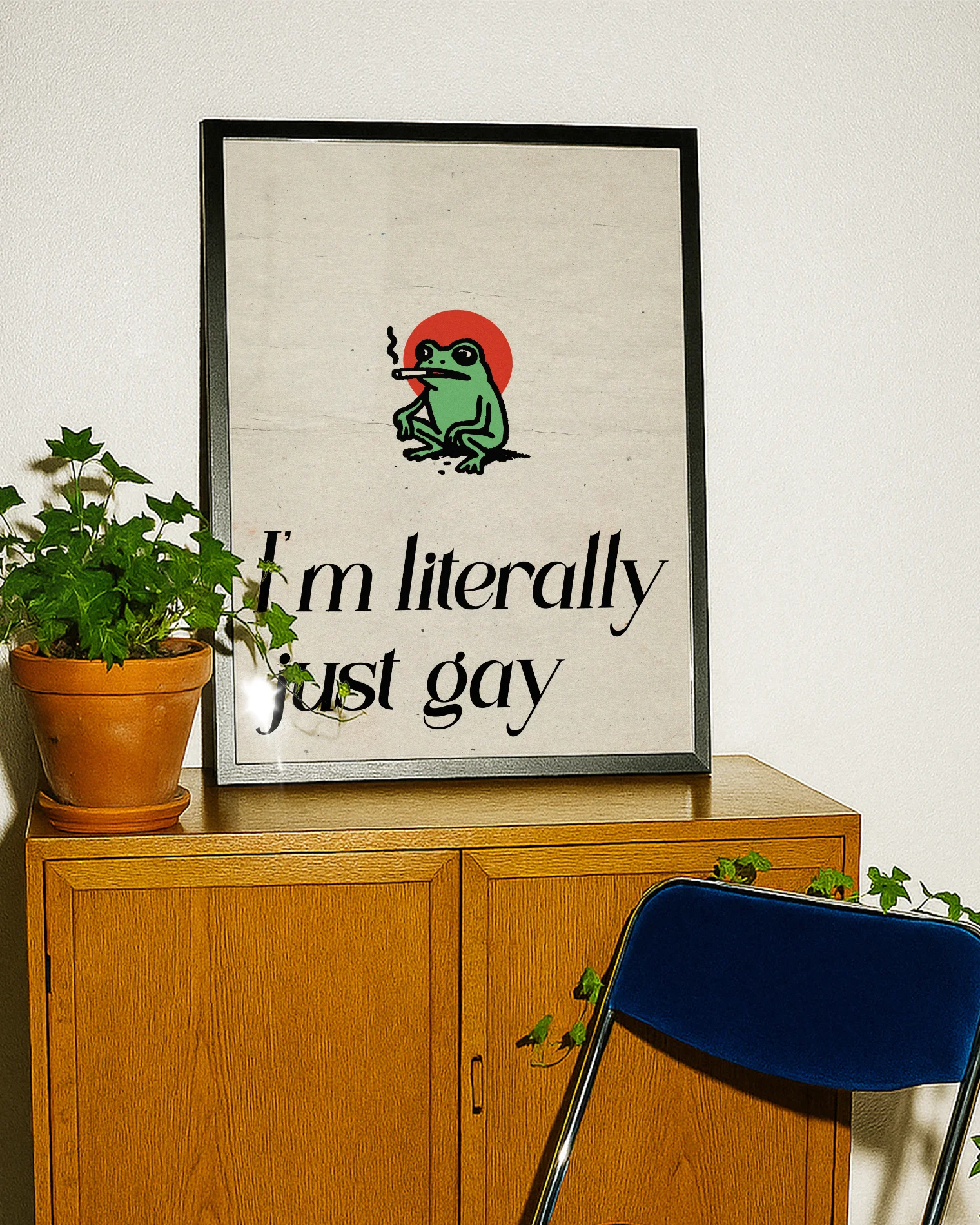 A framed poster with a cute, green, smoking frog with the text 'I´m literally just gay'.