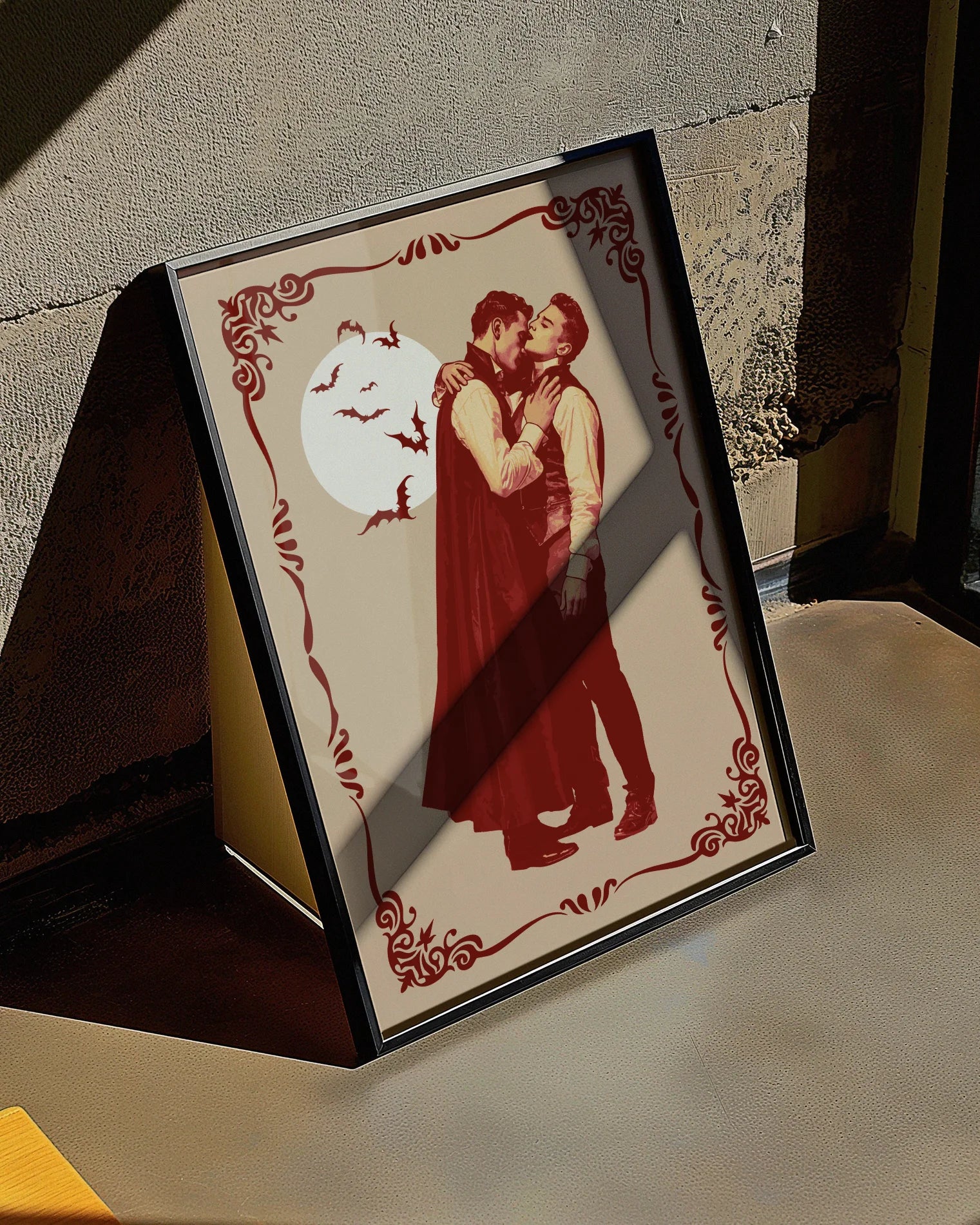 A poster featuring a male vampire kissing another man’s neck, framed by a vintage border, with a full moon and flying bats in the background.