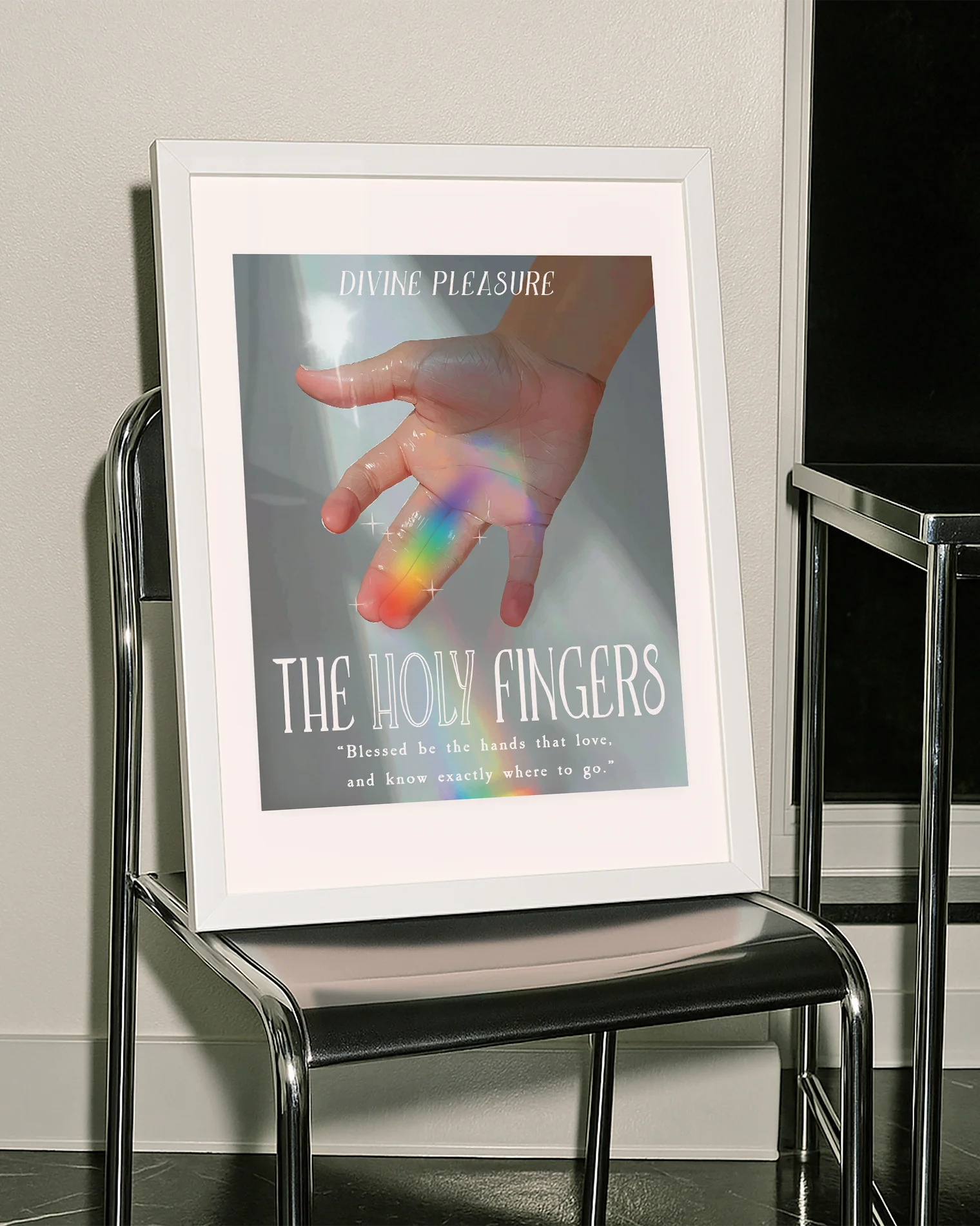 A framed print showing a hand bathed in sunlight, with a ray of rainbow light across the ring and index fingers, with the texts:
“DIVINE PLEASURE – THE HOLY FINGERS” and “Blessed be the hands that love, and know exactly where to go.”