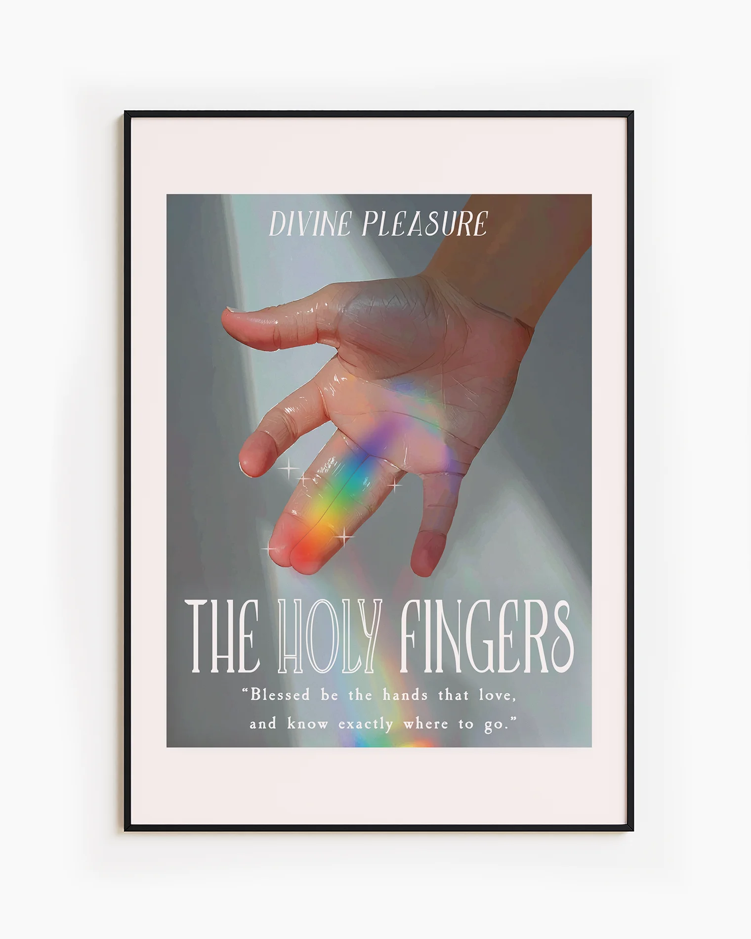 A framed print showing a hand bathed in sunlight, with a ray of rainbow light across the ring and index fingers, with the texts:
“DIVINE PLEASURE – THE HOLY FINGERS” and “Blessed be the hands that love, and know exactly where to go.”