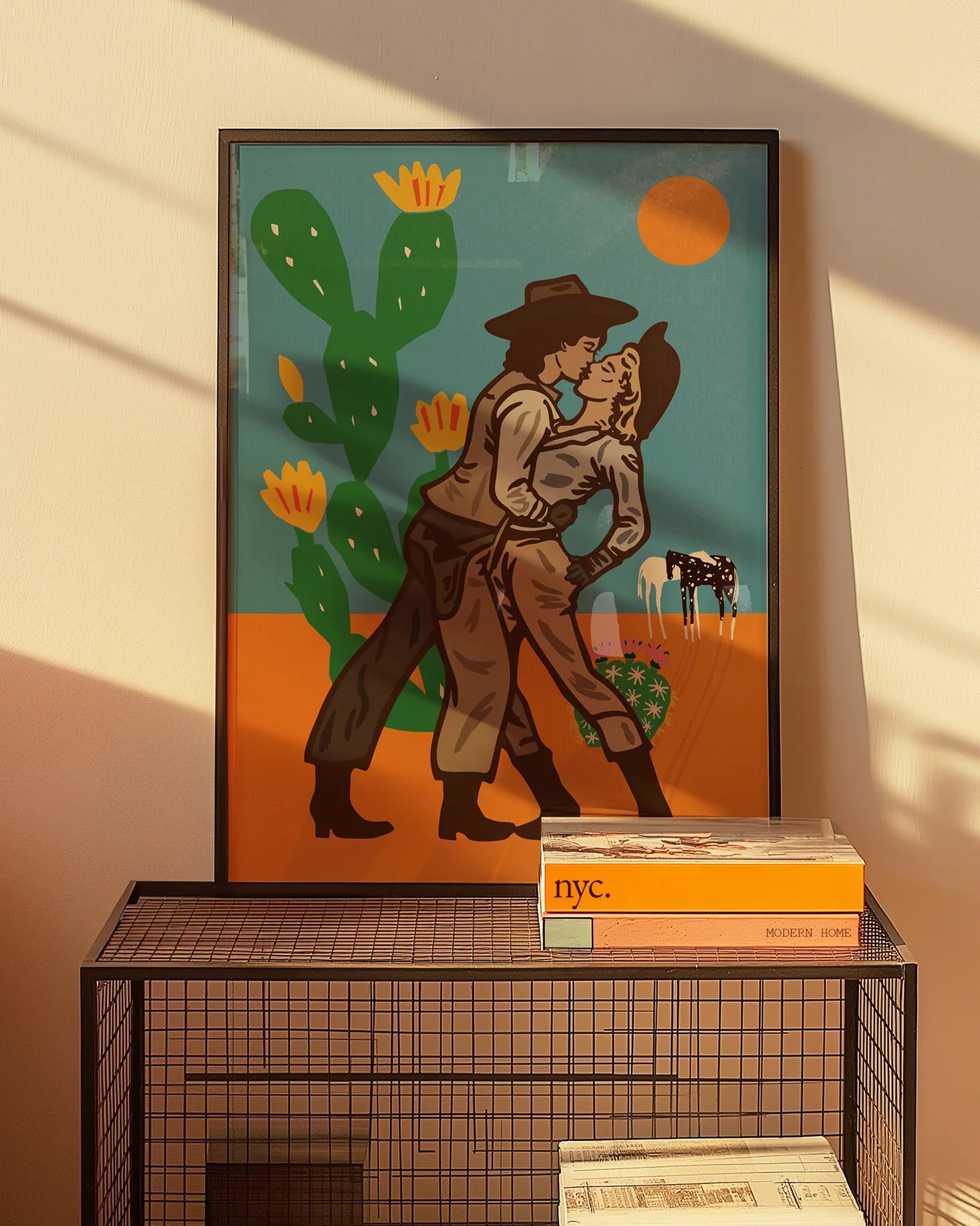 An illustrated print with a lesbian cowgirl couple kissing in the desert.