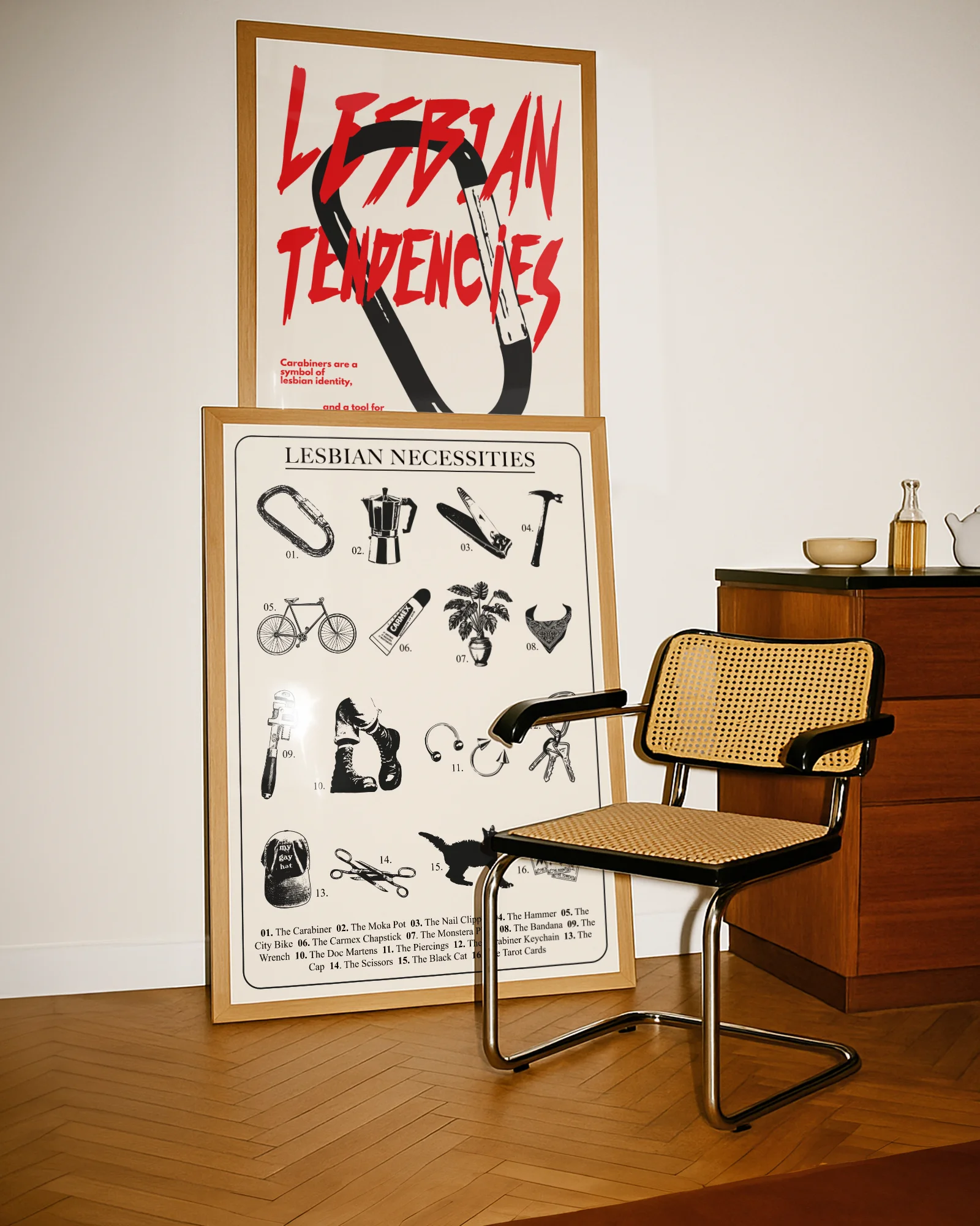 A framed poster with a design featuring 16 iconic and symbolic lesbian necessities and items, all numbered and gathered under the text “LESBIAN NECESSITIES.”