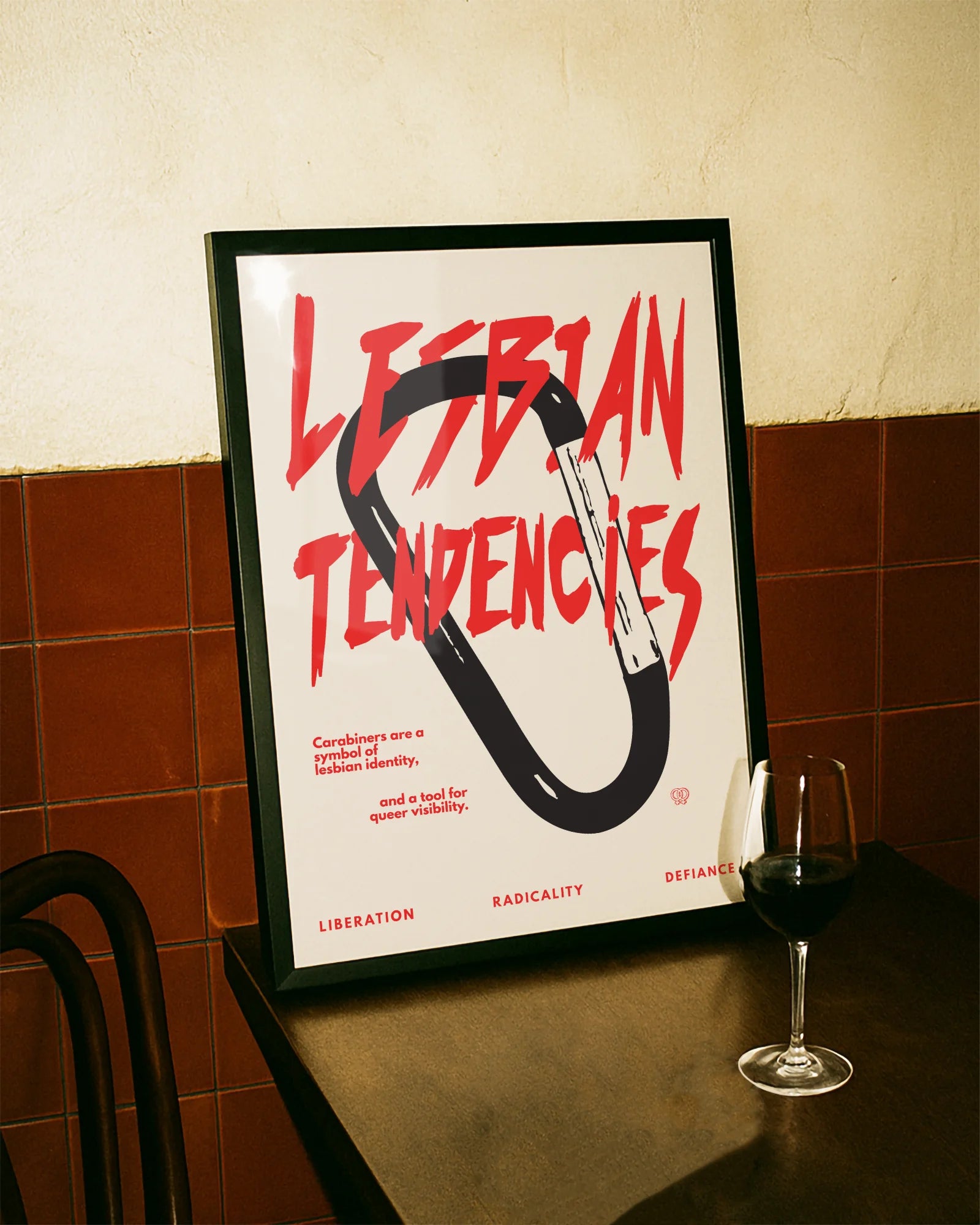 A print with an illustrated carabiner, with the text 'Lesbian Tendencies' in red.