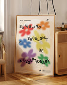 A print with gay pride flowers and the text 'Existing Shouldn't Be Revolutionary'.