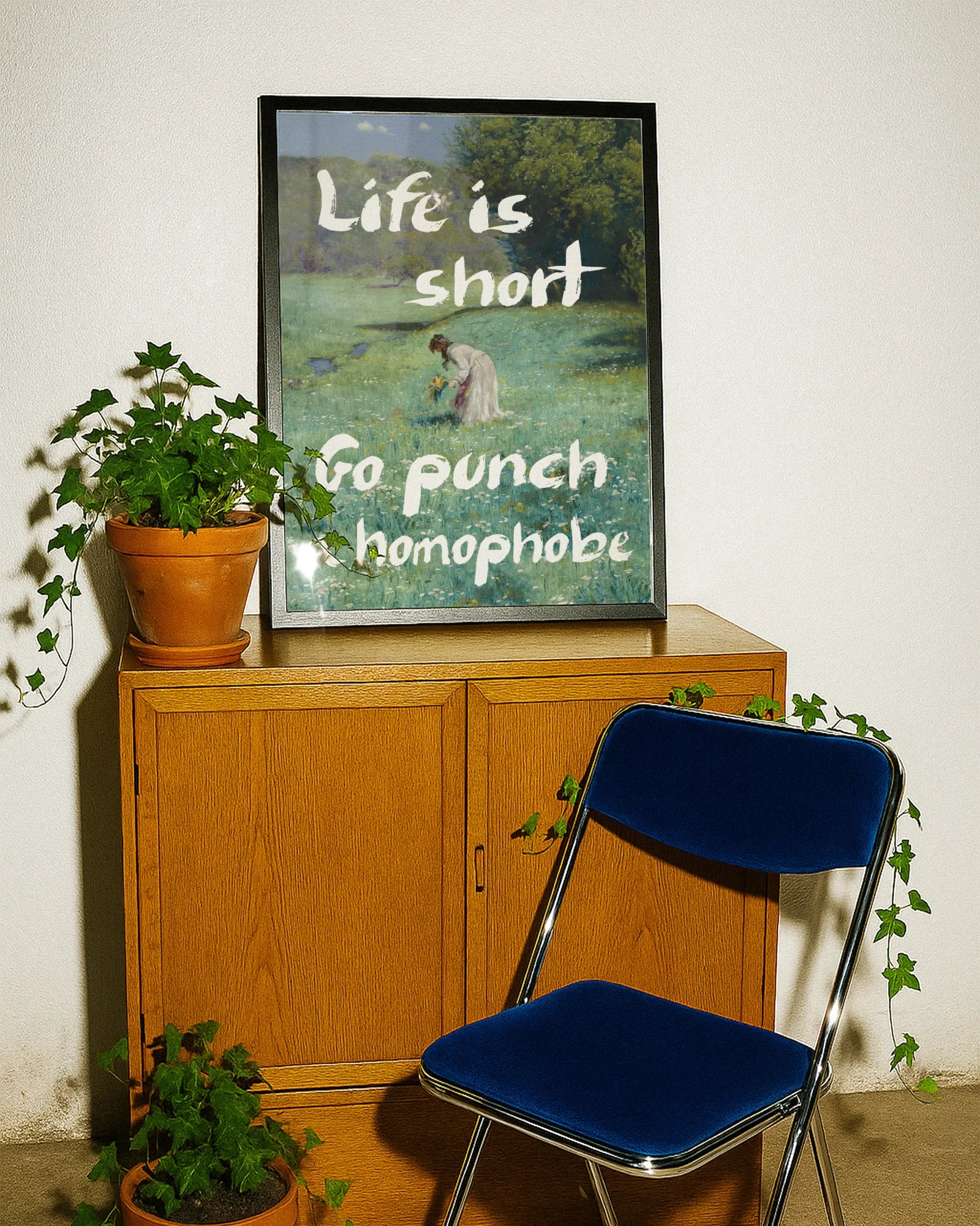 En postern som föreställer en kvinna som plockar blommor i ett öppet fält, i en klassisk oljemålnings-stil med texten 'Life is short Go punch a homophobe".