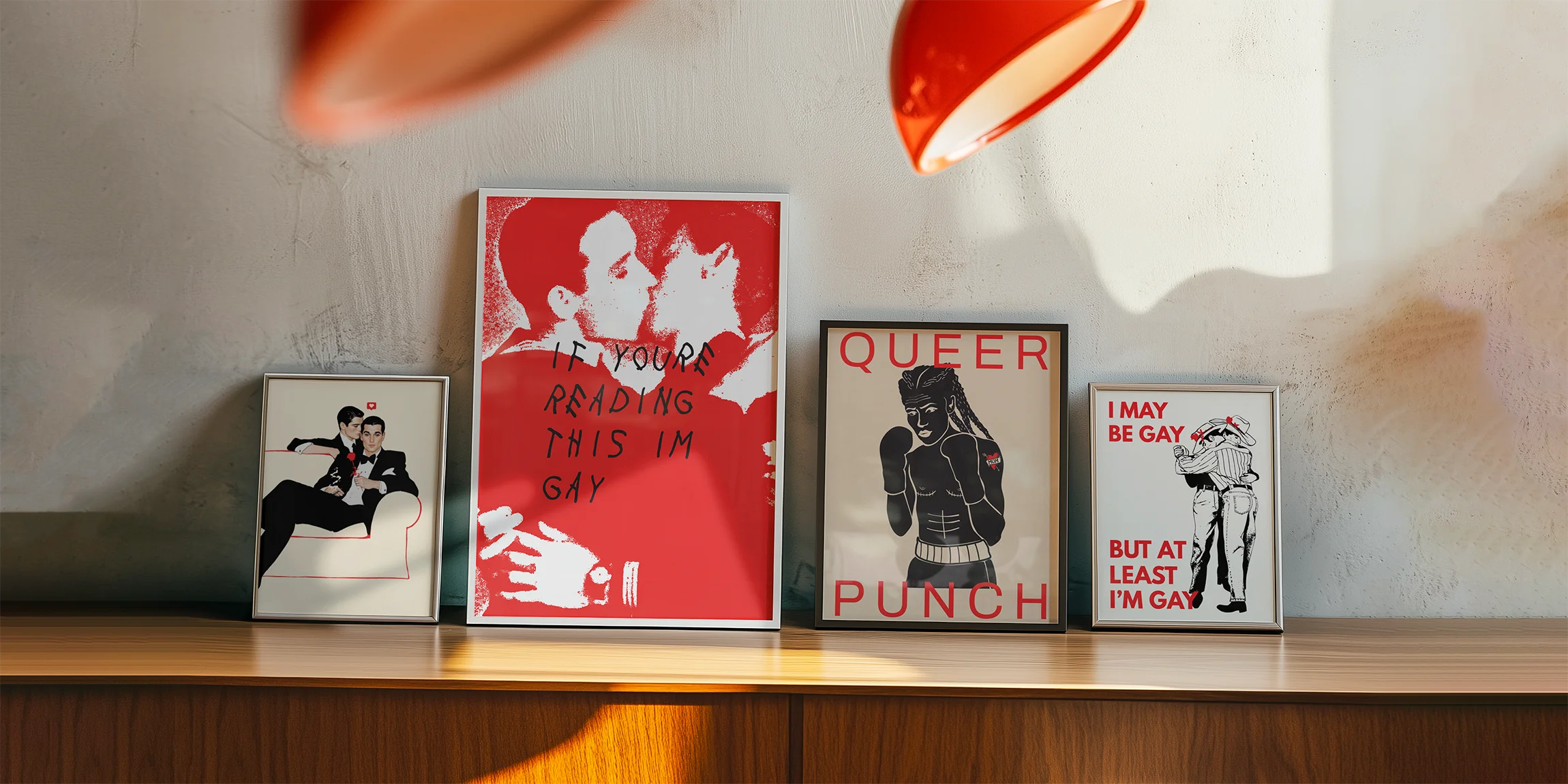 A photo of four framed, fun and queer prints at a sidetable.