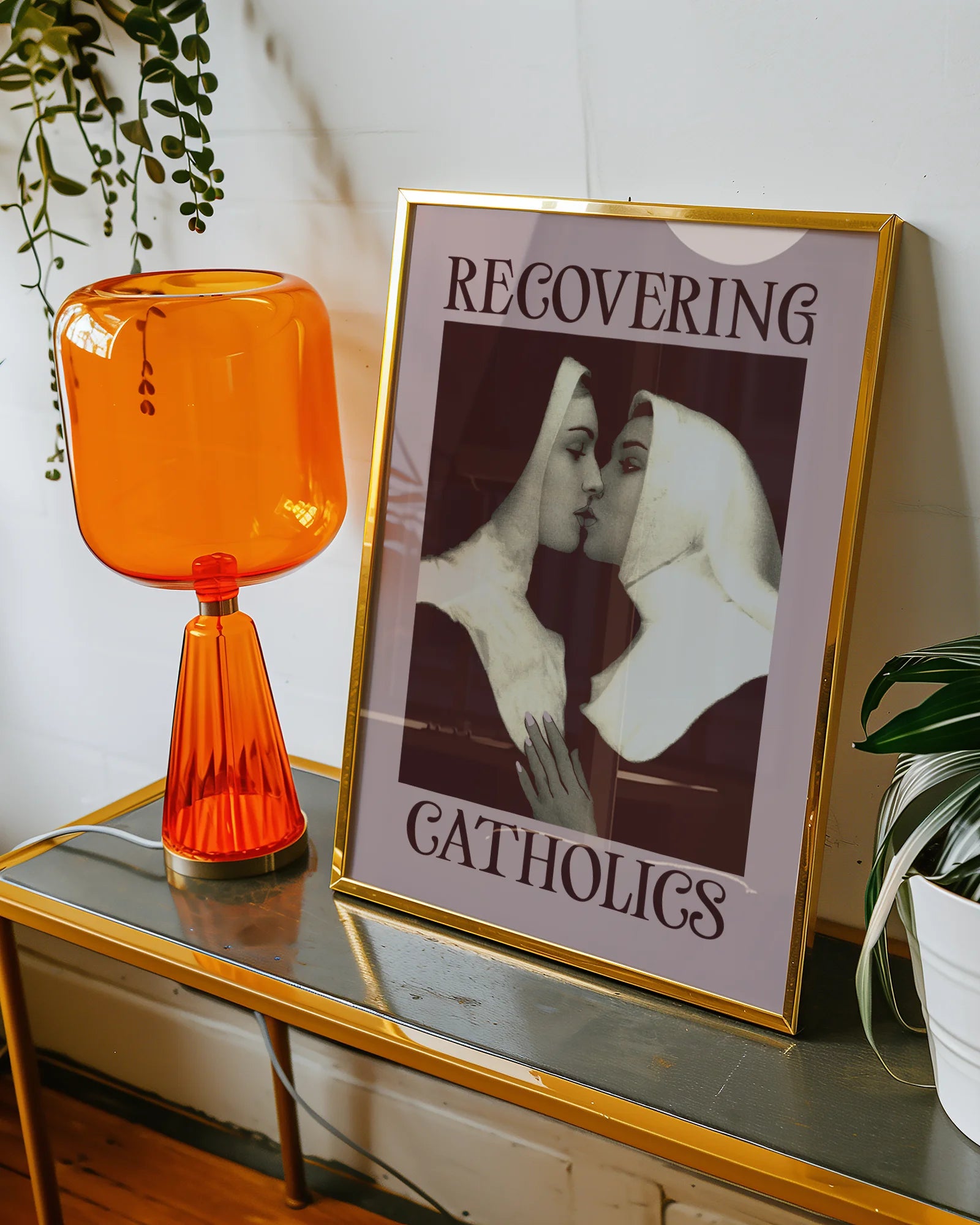 A framed poster featuring two kissing nuns, paired with the text "RECOVERING CATHOLICS."