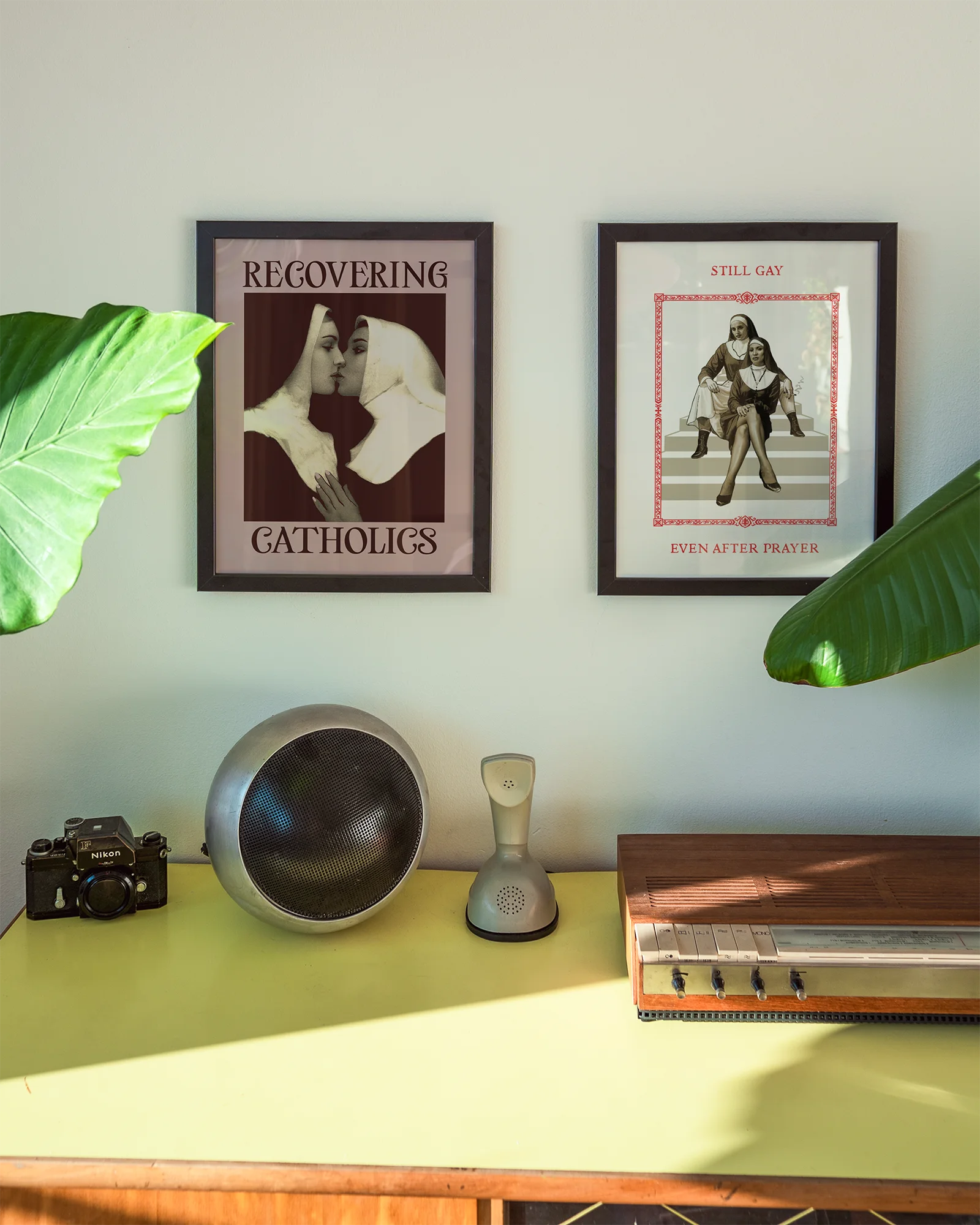 A framed poster featuring two kissing nuns, paired with the text "RECOVERING CATHOLICS."