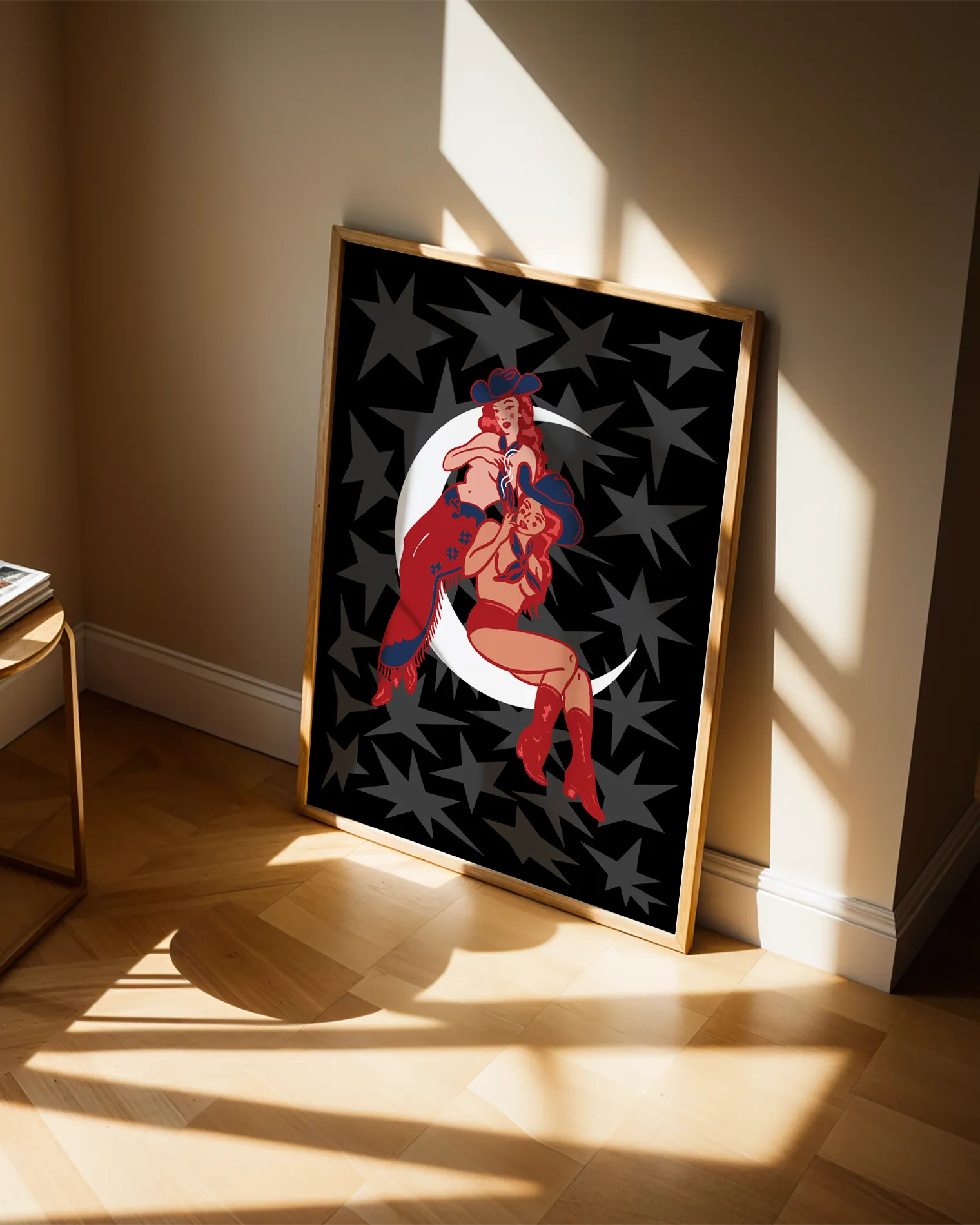 A print with two illustrated, sapphic cowgirls sitting on a moon.