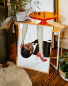 A poster featuring a woman in a blazer, lying on the floor with a cigarette in her mouth, gazing up at another woman standing over her in red heels.