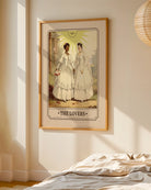 A print with an illustrated, sapphic, newlywed couple in a tarot card style with the text 'The Lovers'.
