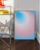 A framed print with a round, gradient form in the transflag colours blue, pink and white.