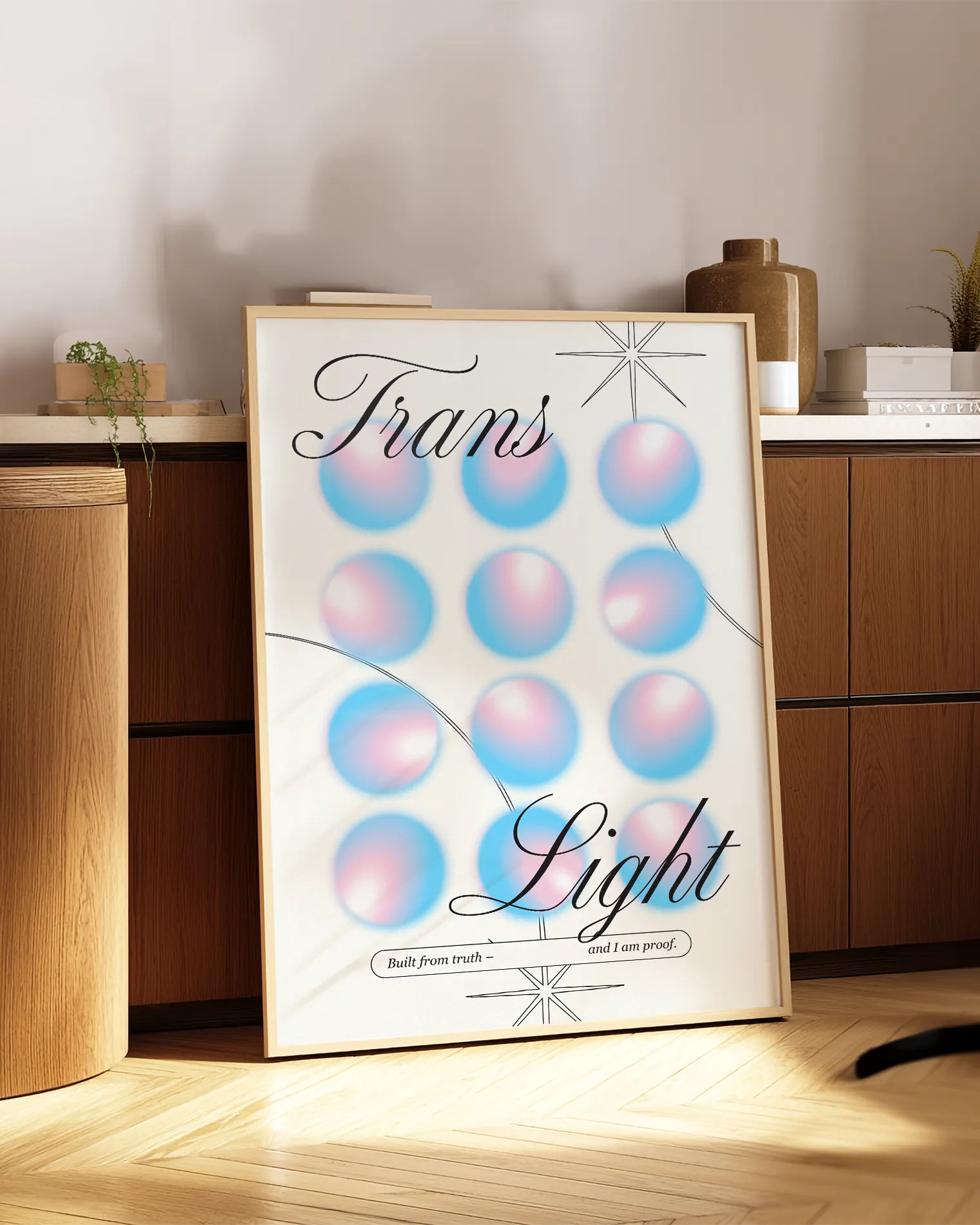 A print with the text 'Trans Light', against a background with gradient circles in the transgender flag colours.