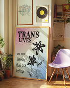A print with the text 'Trans Lives are more important than CIS feelings', against the transgender flag colours.