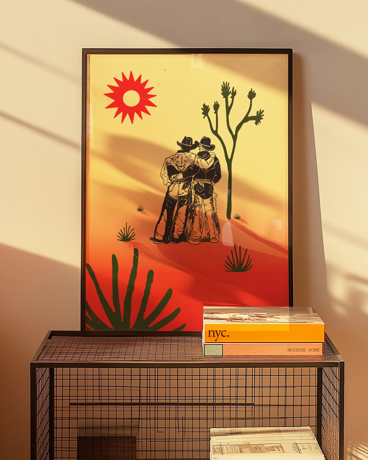 A print with an illustrated cowboys-couple in a desert, surrounded by a red and yellow sunset.