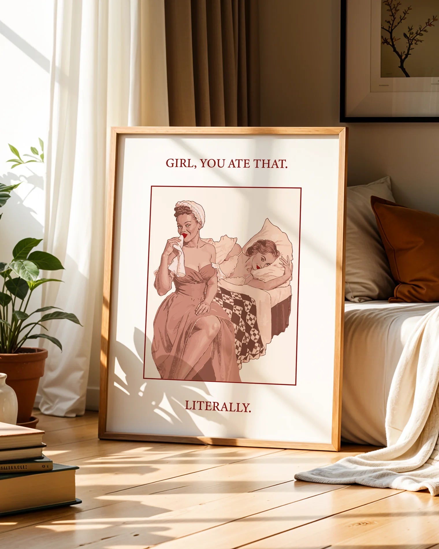 A poster featuring a woman wiping her mouth with a cloth napkin while sitting on the edge of a bed, with another woman lying behind her. Text on the artwork reads: “GIRL, YOU ATE THAT. LITERALLY.”