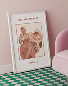 A poster featuring a woman wiping her mouth with a cloth napkin while sitting on the edge of a bed, with another woman lying behind her. Text on the artwork reads: “GIRL, YOU ATE THAT. LITERALLY.”