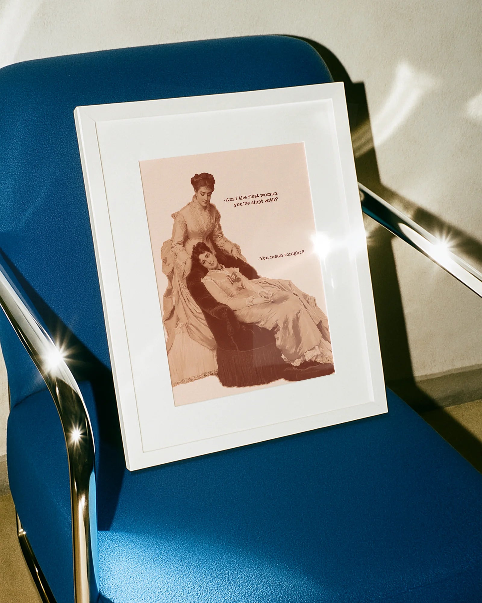 A framed poster featuring two sapphic women from the Victorian era in a conversation: 'Am I the first woman you've slept with?' 'You mean tonight?'.