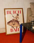 A poster depicting a lesbian woman riding a fish and holding a fishing rod, with the text ‘BUTCH BAIT'.