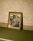 A framed poster with two men cuddling in a park. Vintage, oil painting style.