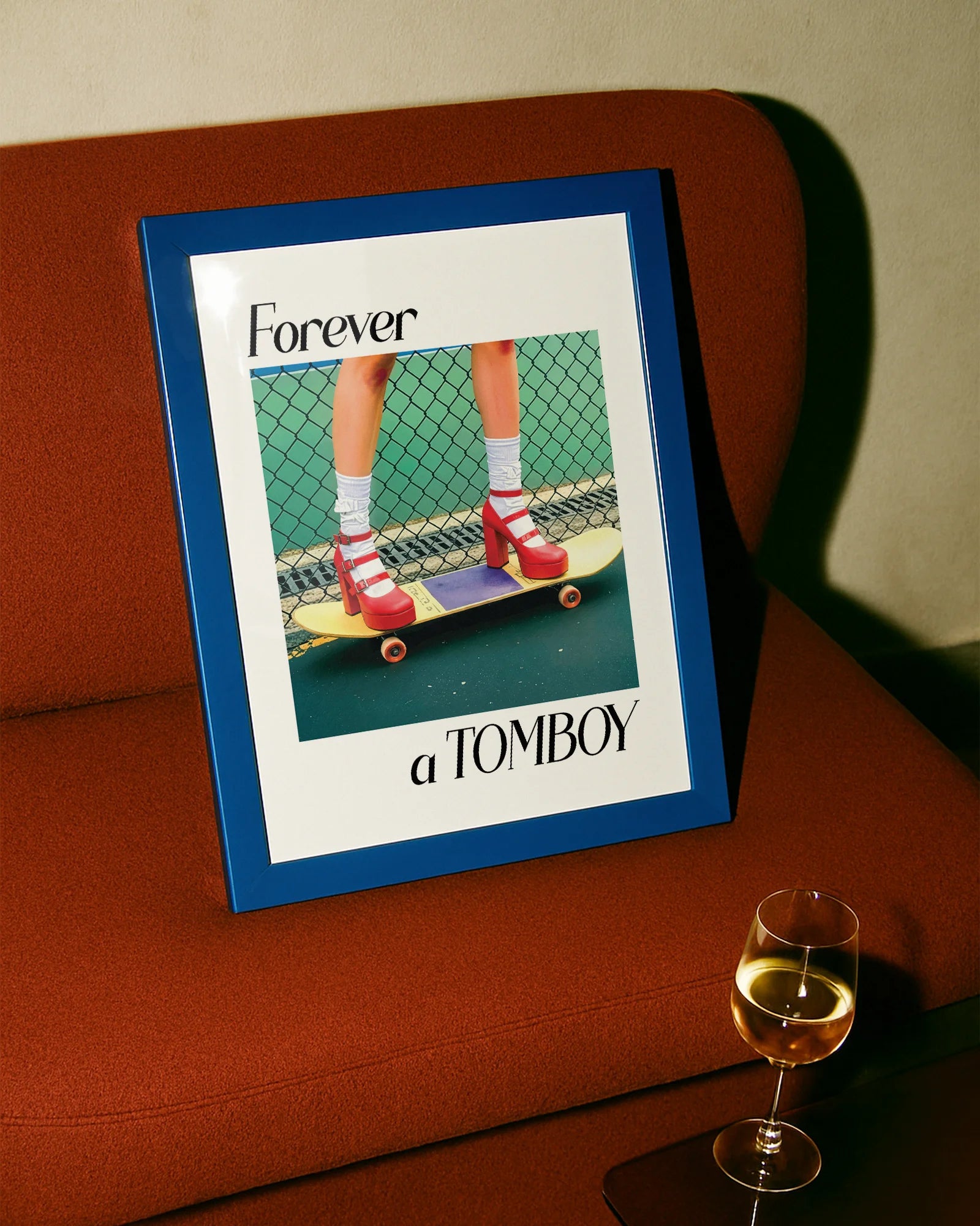 A framed print with a girl in red high heels standing on a skateboard, with the text: 'Forever a TOMBOY'.