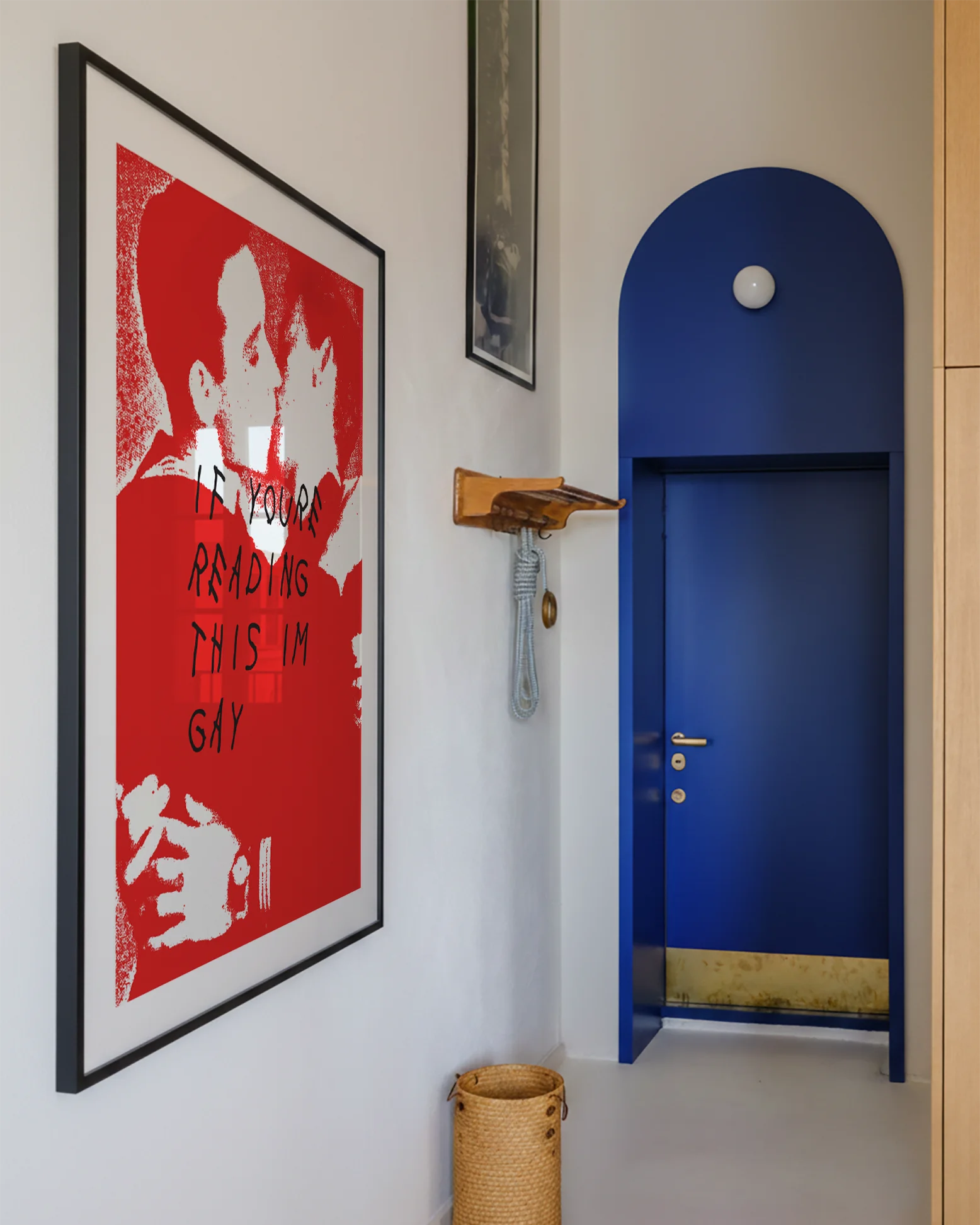 A photo with a framed, queer poster in a hallway.