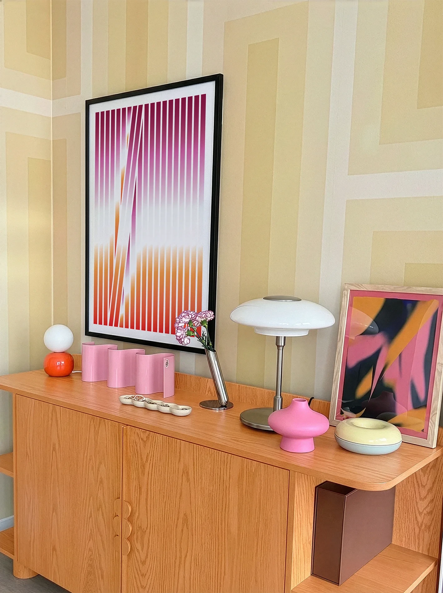 A gallery wall with several framed, queer posters in a living room.