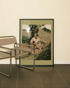 A framed poster with two men cuddling in a park. Vintage, oil painting style.