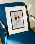 A framed print with two naked girls, hugging tight on the floor.