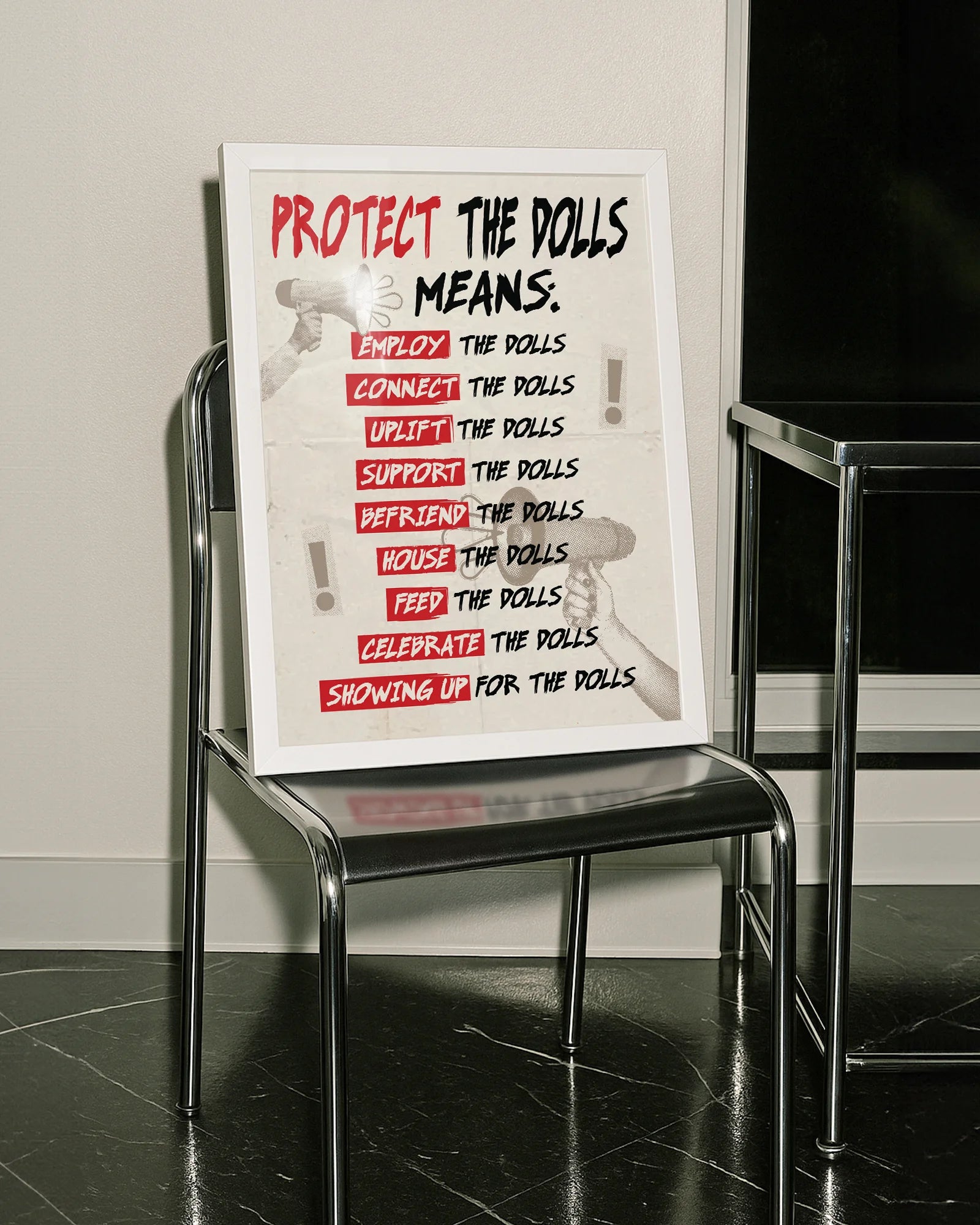 A framed print featuring the text “PROTECT THE DOLLS MEANS:” followed by:
employ the dolls
connect the dolls
uplift the dolls
support the dolls
befriend the dolls
house the dolls
feed the dolls
celebrate the dolls
showing up for the dolls