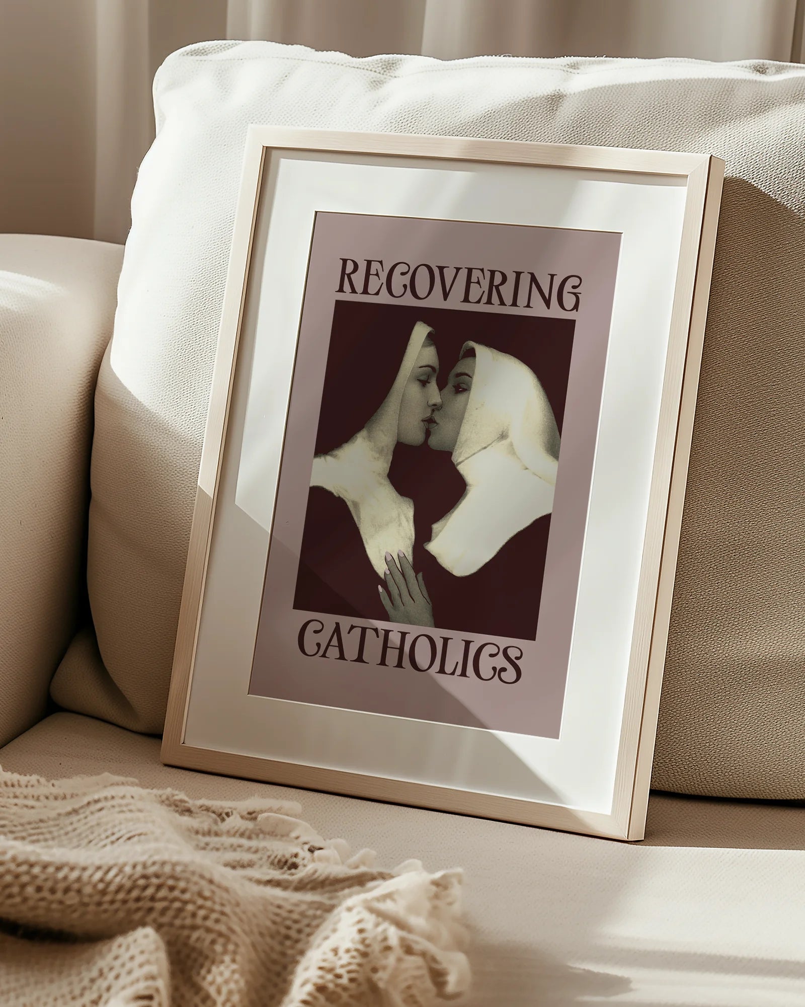 A framed poster featuring two kissing nuns, paired with the text "RECOVERING CATHOLICS."