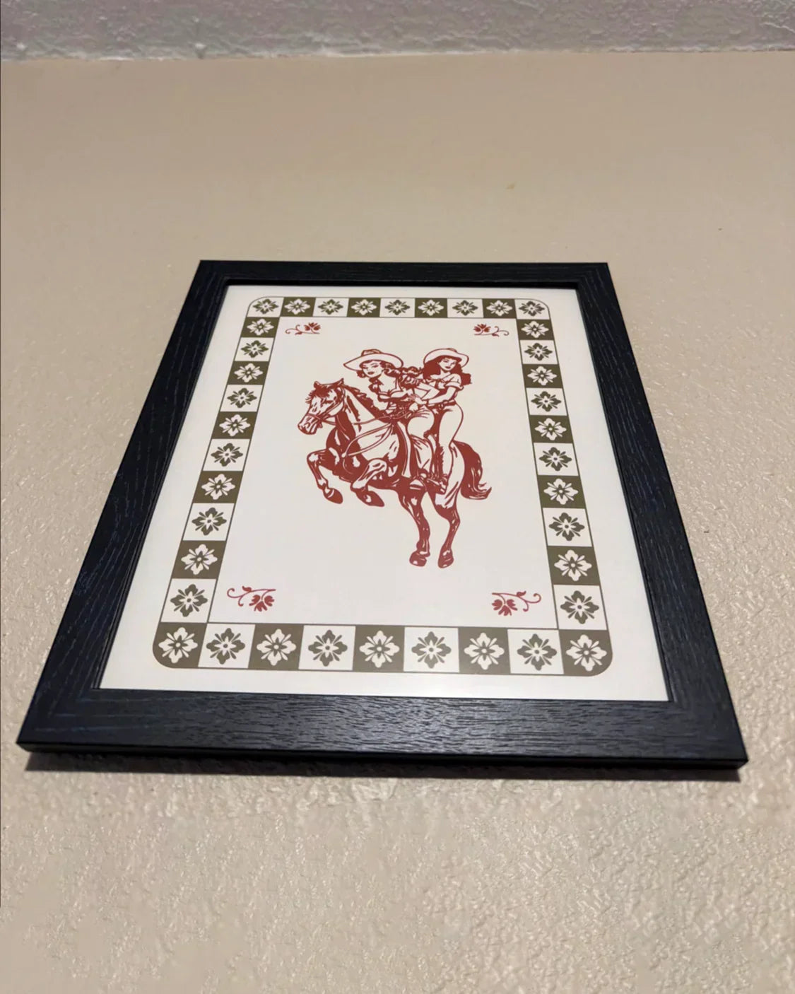 A photo from a customer, showing a framed poster with two lesbian cowgirls.
