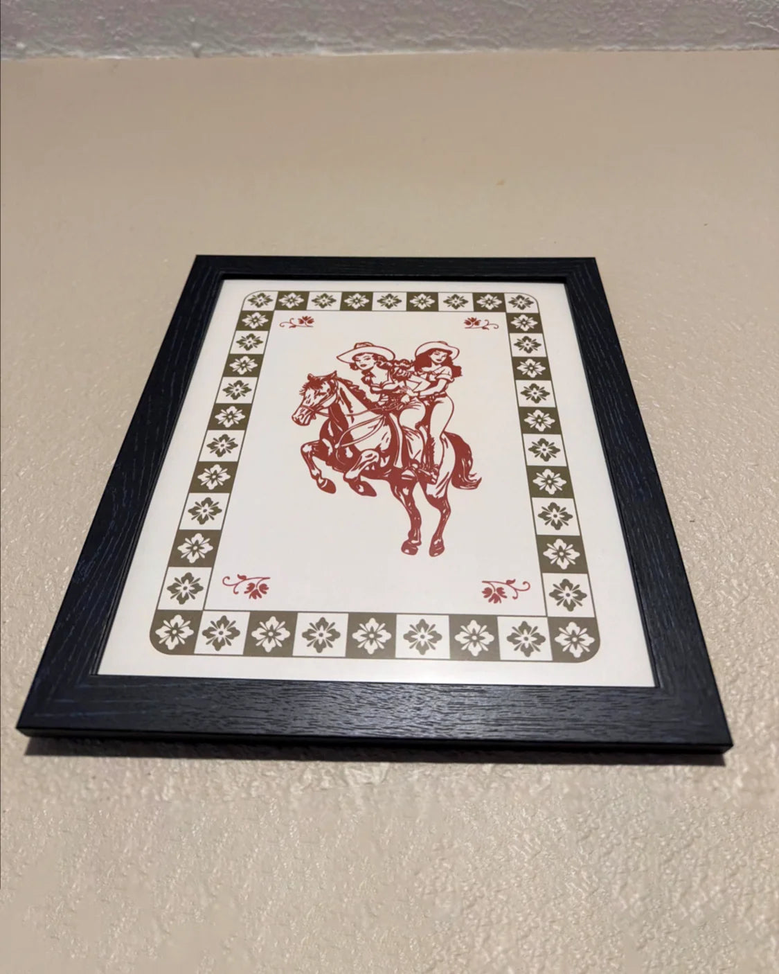 A photo from a customer, showing a framed poster with two lesbian cowgirls.