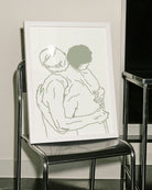 A framed poster with two naked men hugging, lineart style.
