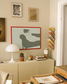 A framed, horizontal poster with two naked, lesbian ladies hugging tight on a couch.