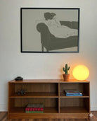 A framed, horizontal poster with two naked, lesbian ladies hugging tight on a couch.