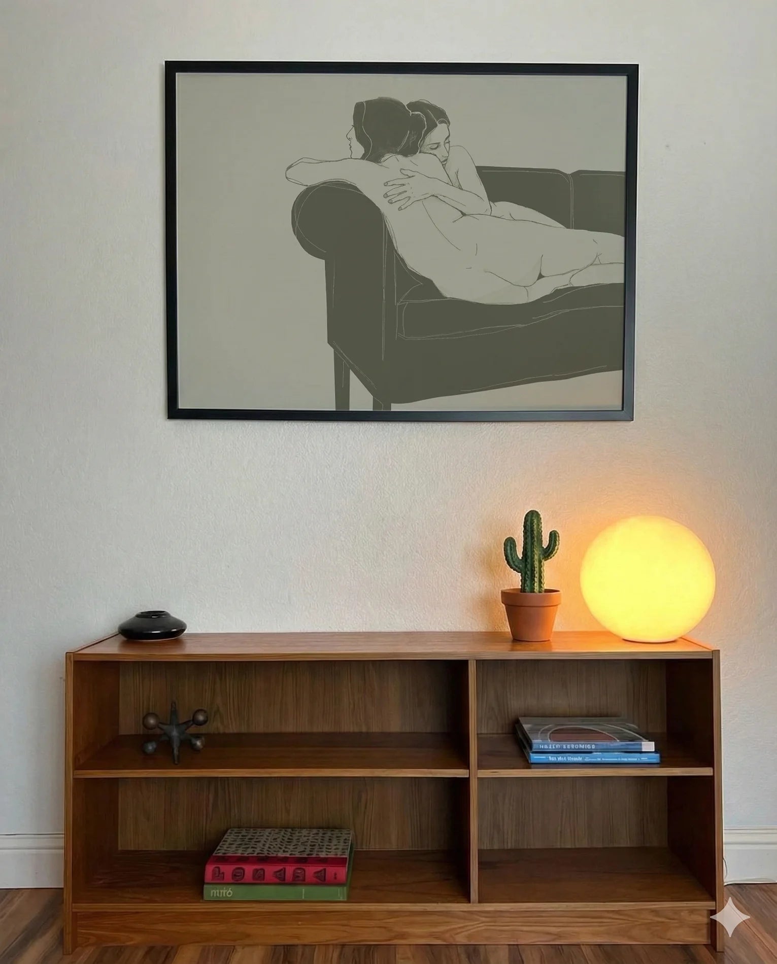 A framed, horizontal poster with two naked, lesbian ladies hugging tight on a couch.