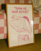 A poster of a woman removing her shirt with the text "SHOW ME YOUR KITTIES".