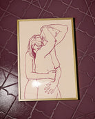 A framed print with two lesbian, naked girls hugging.